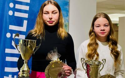 Vuoden 2022 urheilija ja junioriurheilija poseeraavat pokaalien kanssa